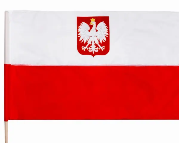 Flaga Polski z orłem w koronie na białym tle. Duma narodowa na drewnianym kiju.