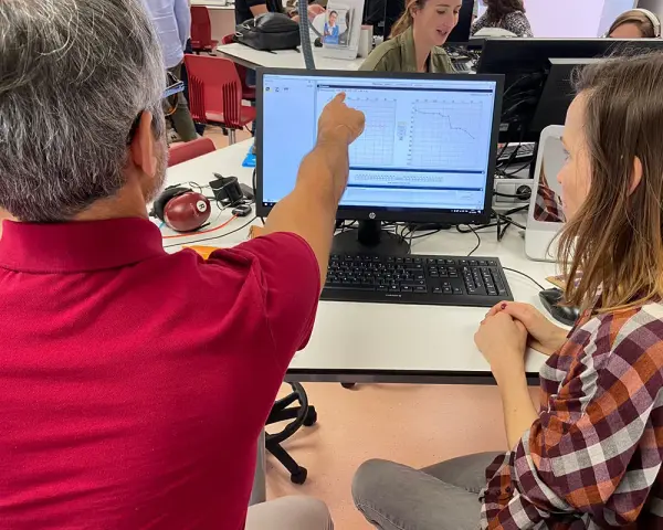 Un homme montre un audiogramme à une femme, lors d'une formation audioprothésiste Espagne à distance.
