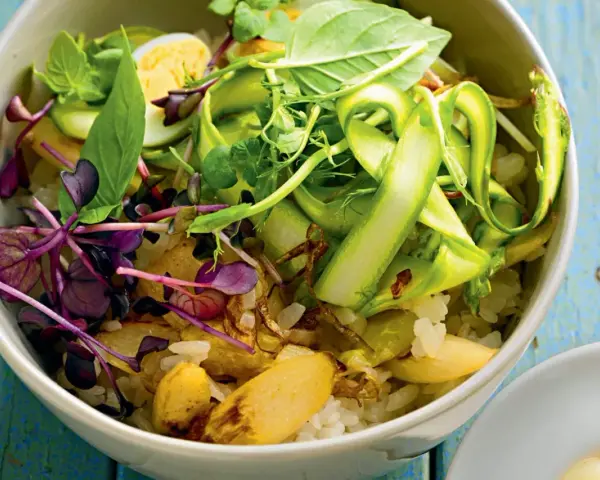Eine bunte Spargel Bowl mit Reis, Ei, Sprossen und frischen Kräutern, appetitlich angerichtet.