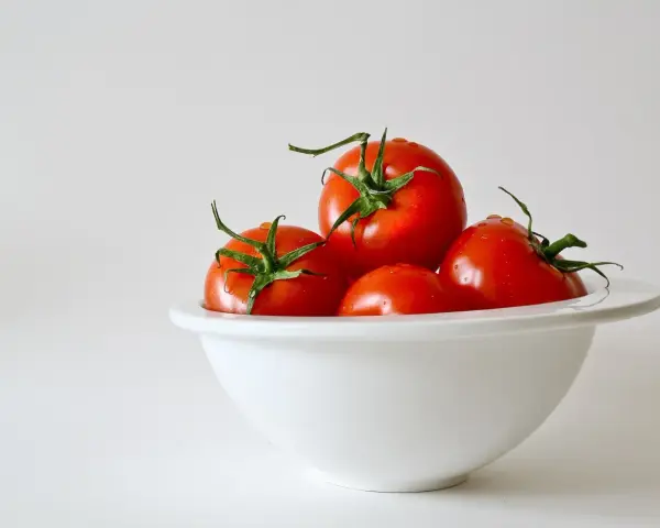 Kilka soczystych pomidorów w białej misce. Niska zawartość pomidor kcal sprawia, że są idealne na zdrową przekąskę.