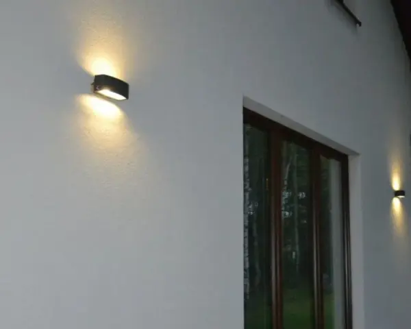 Nierówności na elewacji pod światło, podkreślone przez dwa kinkietowe punkty świetlne.