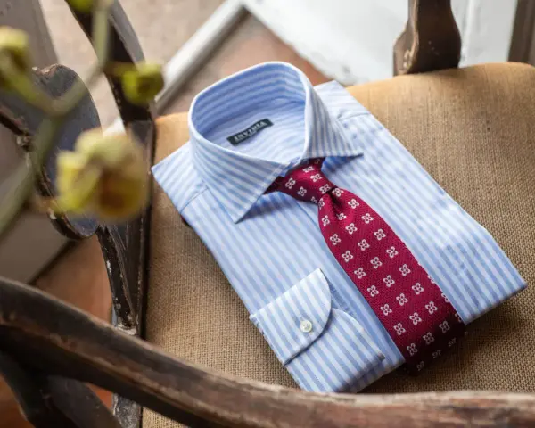 Camicia bianca a righe azzurre con cravatta bordeaux a fantasia floreale, pronta per un abito blu.