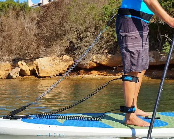 Person befestigt sup leash an Hüfte und Bein für sicheren Stand auf dem Board.