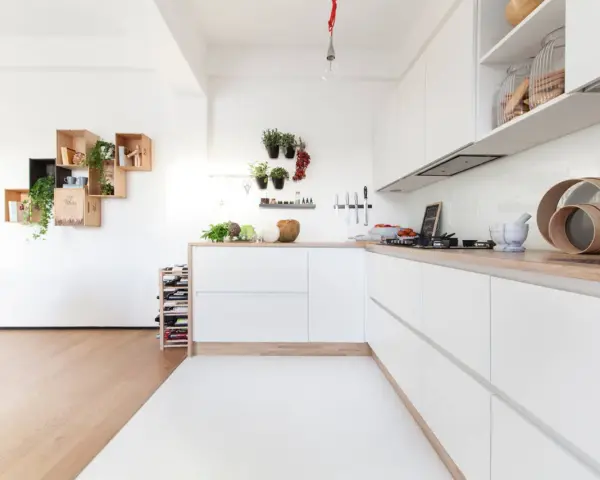 Progetto cucina angolare piccola: mobili bianchi minimalisti, piano in legno, mensole a muro con piante e vasi.