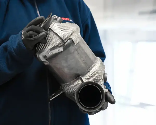 Osoba w rękawiczkach trzyma filtr cząstek stałych DPF.