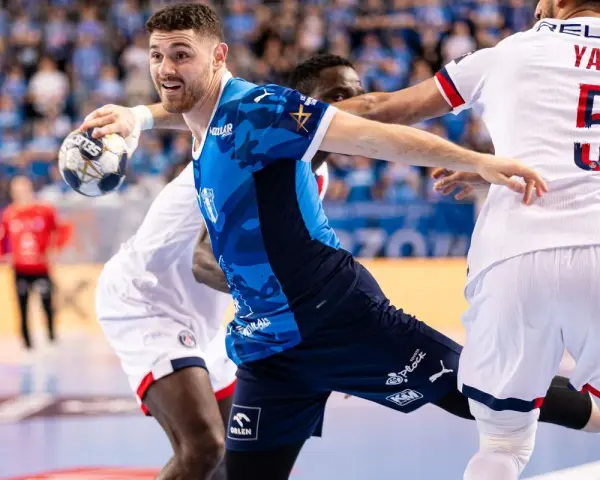 Piłkarz Wisły Płock w akcji przeciwko PSG. Zawodnik w niebieskiej koszulce z piłką w ręku, gotowy do rzutu.