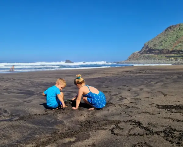 Dzieci budują zamki z piasku na czarnej plaży. Teneryfa atrakcje dla dzieci to raj dla małych odkrywców.