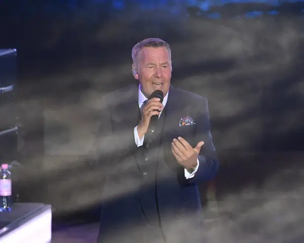 Roland Kaiser singt in Berlin. Der Künstler trägt einen dunklen Anzug und hält ein Mikrofon.