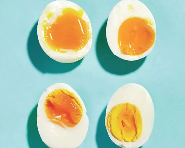 Quatre moitiés d'oeuf à la coque sur fond bleu. Deux ont un jaune coulant, les autres un jaune plus ferme.