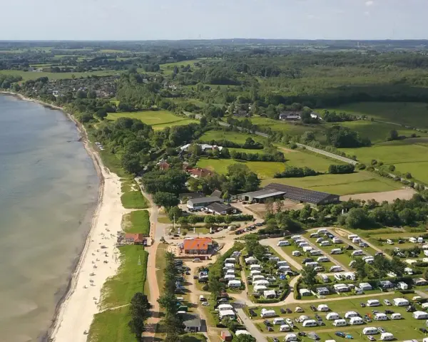 Luftaufnahme eines Campingplatzes in Schleswig-Holstein mit Wohnmobilen und Zelten, direkt am sandigen Strand und dem Meer gelegen.