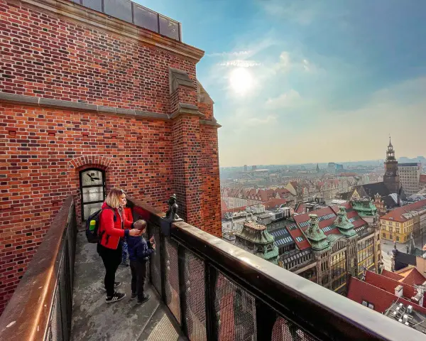 Kobieta z dzieckiem na moście pokutnic, podziwiający panoramę miasta.