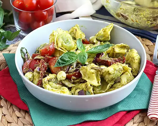 Miseczka tortellini z pesto, pomidorkami koktajlowymi i bazylią.