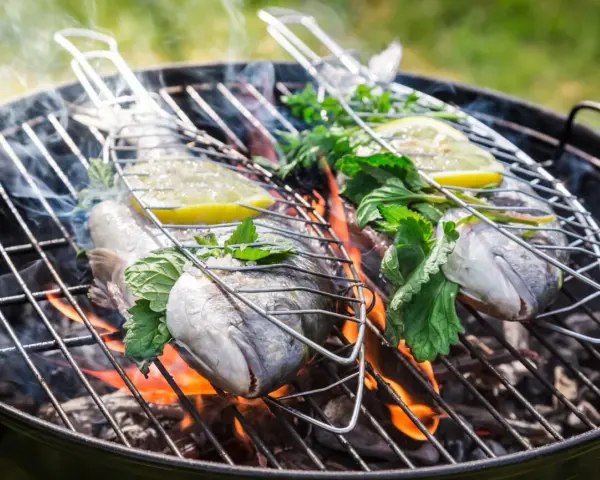 Dwie ryby na grillu, z cytryną i ziołami, unoszą się nad ogniem. Idealna jaka ryba na grilla na letni wieczór.
