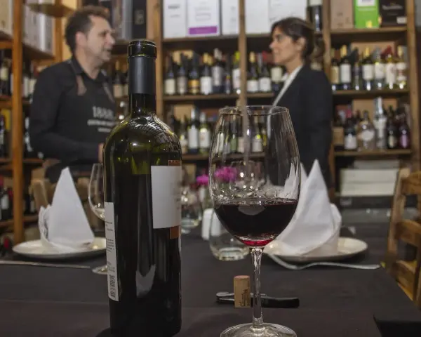 Winiarnia, butelka i kieliszek czerwonego wina na stole. Zastanawiasz się, czy można przewozić alkohol w bagażu rejestrowanym?
