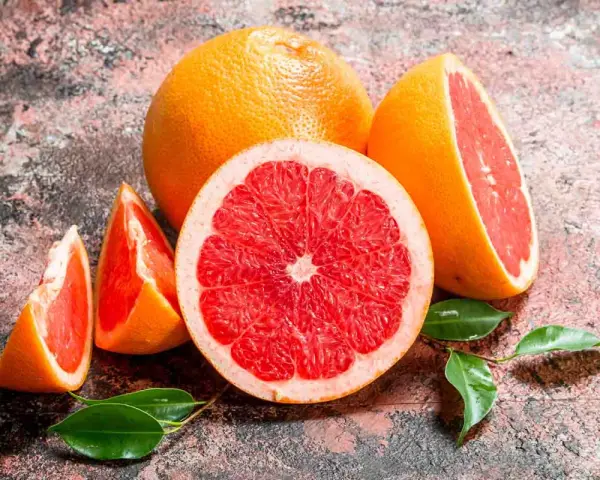 Saftige Grapefruits, frisch aufgeschnitten und als Spalten, mit grünen Blättern. Grapefruit gesund und lecker.