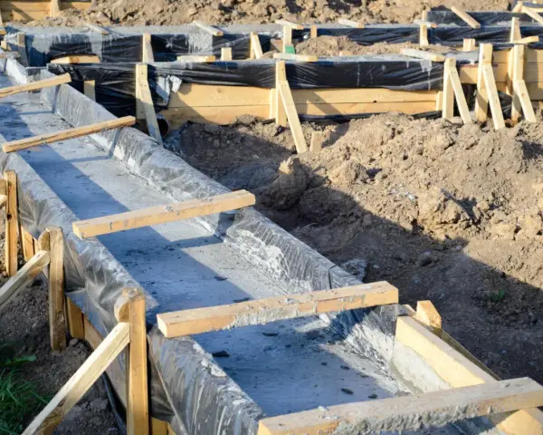 Budowa fundamentów: betonowe ławy w drewnianym szalunku, wyłożone czarną folią.