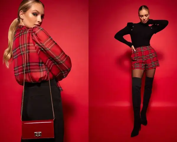 Modelka w czerwonym, kraciastym kiltcie i czarnym sweterku. Obok druga modelka w kraciastej bluzce i czarnych spodniach.