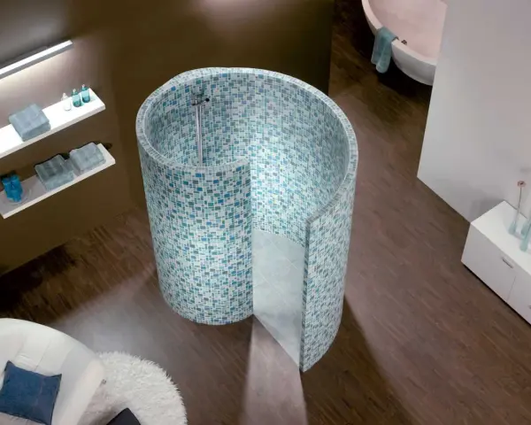 Une douche escargot aux mosaïques bleues et vertes, avec une baignoire et un fauteuil dans une salle de bain moderne.