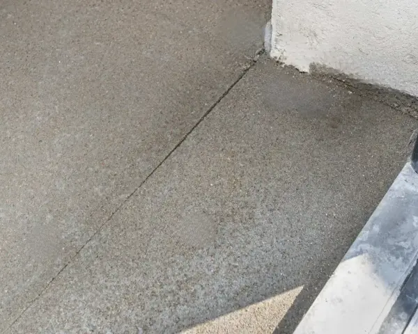 Szara posadzka betonowa z widocznym nacięciem, które zapobiega pękaniu. To właśnie jest dylatacja, która pozwala materiałowi pracować.