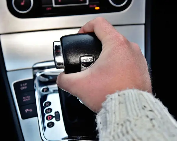 Dłoń trzymająca dźwignię zmiany biegów skrzyni DSG. Widoczne przyciski ESP OFF, AUTO HOLD i P.