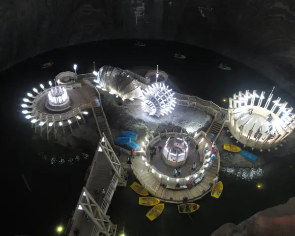 Podziemne jezioro w **Salina Turda** z łódkami i oświetlonymi platformami.