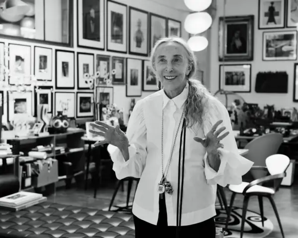 Donna elegante con camicia bianca, un'icona di stile che incarna la moda di Milano. Le sue mani aperte raccontano storie di creatività e design.