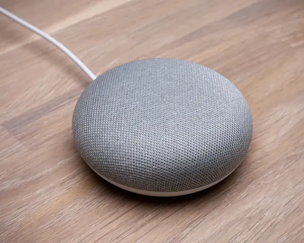 En grå Google Home Mini på ett trägolv, redo att styra ditt smarta hem med Verisure.