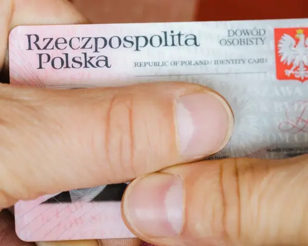 Dłonie trzymają polski dowód osobisty. Widoczny jest numer dowodu osobistego.
