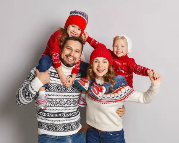 Famiglia felice con maglioni natalizi coordinati, un'ottima ispirazione per idee outfit natale.