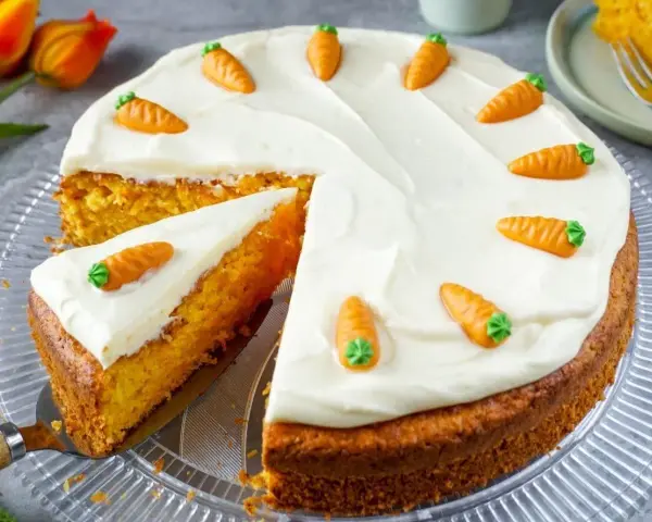 Saftiger karottenkuchen mit cremigem Frosting, dekoriert mit kleinen Marzipankarotten. Ein köstlicher Genuss!