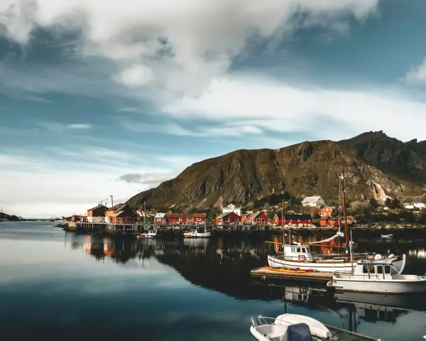 Malowniczy port w Norwegii z czerwonymi domkami i łodziami. Czy do Norwegii trzeba mieć paszport? Sprawdź przed podróżą!