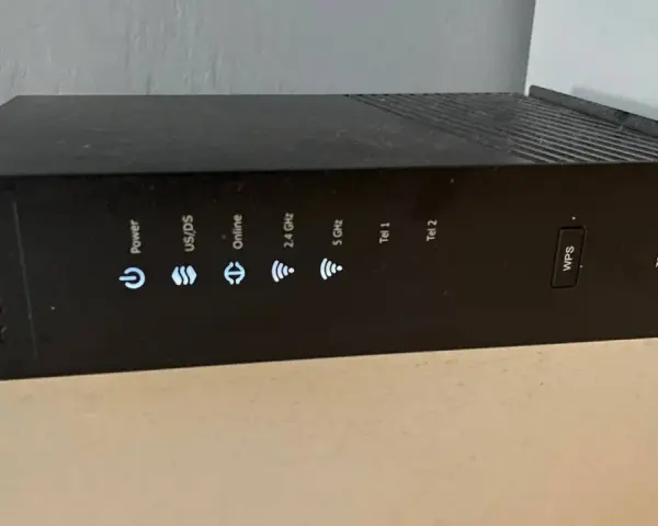 Czarny router Arris TG2492 z widocznym przyciskiem WPS i wskaźnikami stanu: Power, US/DS, Online, 2.4 GHz, 5 GHz, Tel 1, Tel 2.