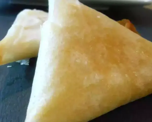 Deux samoussas dorés, un délice croustillant de brick chevre miel, prêts à être dégustés.