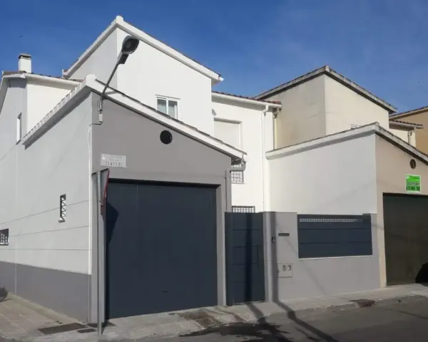 Fachada de casa con garaje, lista para como pintar una pared exterior en mal estado.