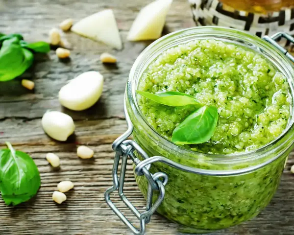 Frisches Pesto machen: Basilikum, Pinienkerne, Knoblauch und Parmesan auf rustikalem Holz.