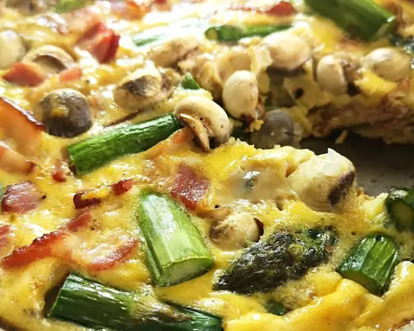 Pyszny stek ze szparagami, boczkiem i pieczarkami zapieczony w jajku. Idealny na śniadanie lub lekki obiad.
