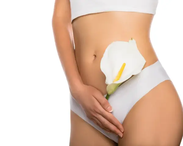 Kobieta w białej bieliźnie trzyma białą kalę. Efekt labioplastyki laserowej przed i po.