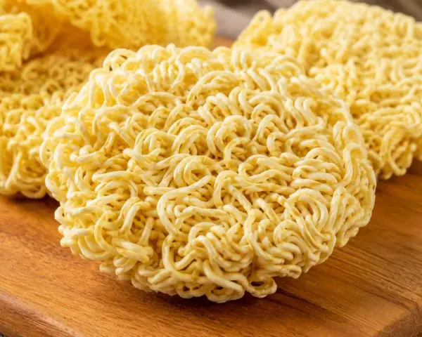 Suszone kluski do ramen na drewnianej desce. Idealne do szybkiego przygotowania pysznego dania.