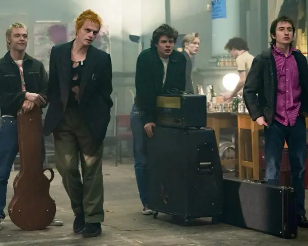 Les membres des Sex Pistols se tiennent prêts pour un concert, guitare et amplis à portée de main.