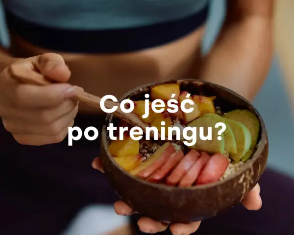 Miseczka z owocami i napisem "Co jeść po treningu?". Zdrowy posiłek regeneracyjny.