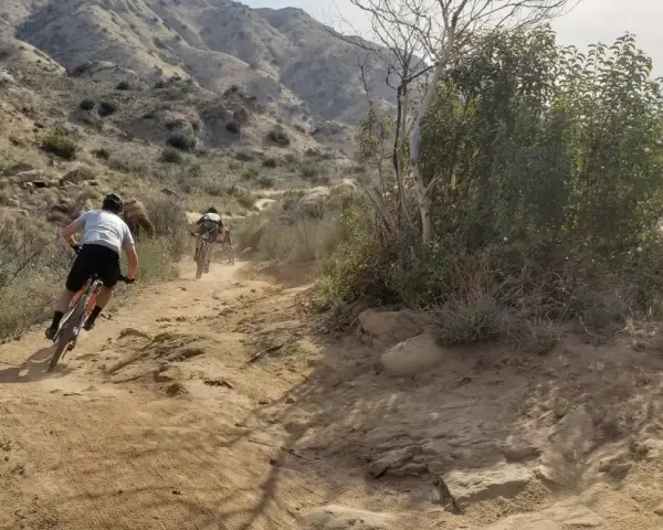Dust flies as cyclists tackle a rugged trail, enjoying mountain biking in Los Angeles.