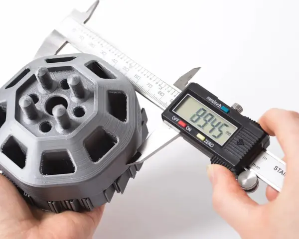 A caliper measures a 3D printed part, showcasing the precision of 3D printing.