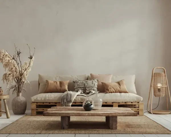 Un divano in pallet e un tavolino grezzo creano un'atmosfera rilassata in stile wabi sabi, con cuscini morbidi e decorazioni naturali.
