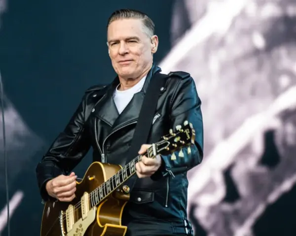 Bryan Adams w skórzanej kurtce gra na gitarze, przypominając piosenkę z Robin Hooda.