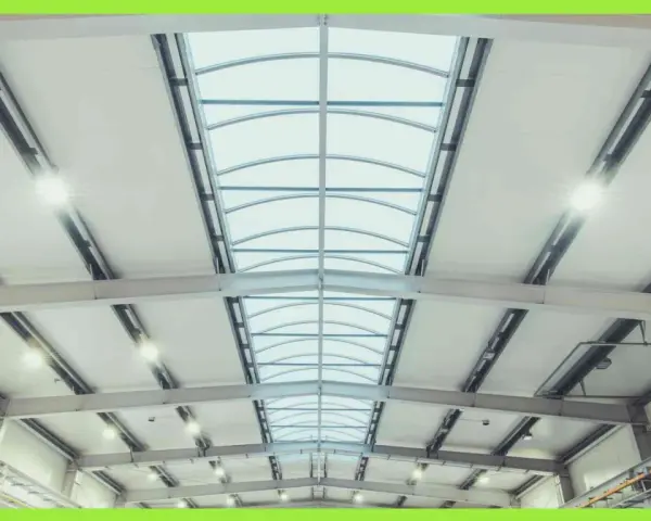 Interno di un capannone con luminose coperture industriali e lucernari curvi che illuminano lo spazio.