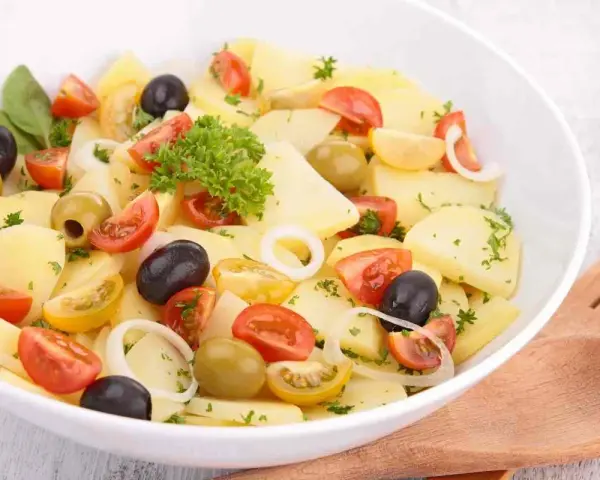 Insalata di patate pugliese con pomodorini, olive nere e verdi, cipolla e prezzemolo fresco. Un piatto estivo e saporito.