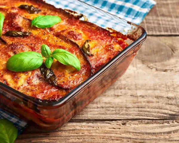 Parmigiana di melanzane in friggitrice ad aria, dorata e profumata, guarnita con basilico fresco. Un piatto gustoso e leggero.