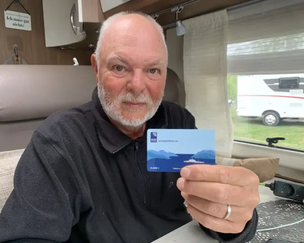 Man håller upp ett kort med texten "autopassferje.no", redo för resor mellan Norge och Sverige.