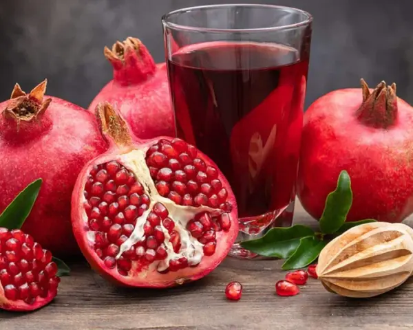 Frische Granatäpfel und Saft auf einem Holztisch. Ein gesunder Genuss, besonders in der Schwangerschaft.