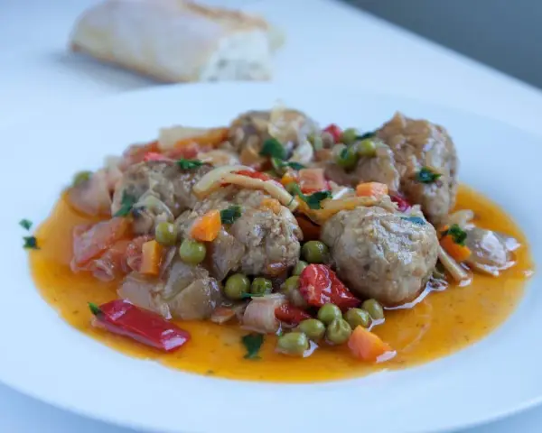 Albondigas a la jardinera, jugosas y sabrosas, con guisantes, zanahoria y pimiento rojo en una salsa dorada.